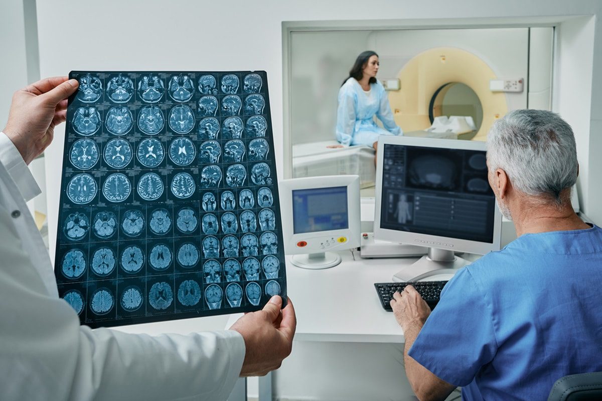 Radiographers analyzing results of CT scan of patient's head are found in control room at hospital radiology department. CT or MRI of human brain. (Credit: iStock)