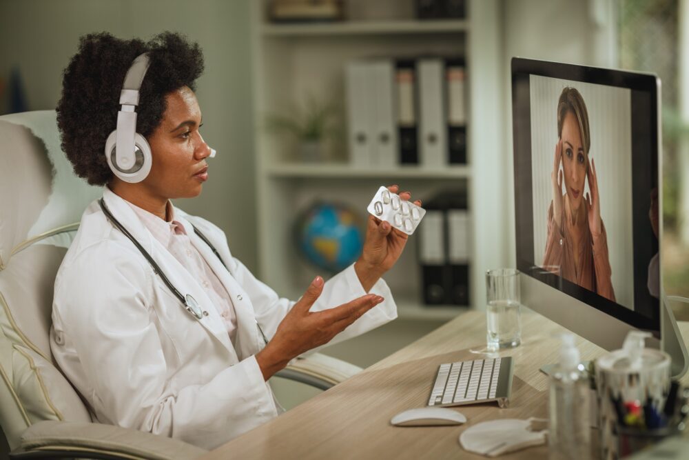 Shot of a doctor having video call with patient on computer in her consulting room during COVID-19 pandemic. Image via Envato.